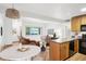 Open-concept living area with wood floors connecting to a breakfast nook, kitchen, and outdoor views at 3663 S Sheridan Blvd # H15, Denver, CO 80235