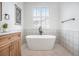 Bright bathroom with standalone tub, tiled walls, tile floors, a decorative print, and a large window at 7410 Winter Berry Ln, Castle Pines, CO 80108