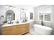 Bright bathroom features a double sink vanity with light wood cabinets and modern fixtures, plus a standalone tub under a window at 7410 Winter Berry Ln, Castle Pines, CO 80108