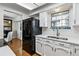 Charming kitchen with white cabinets, quartz countertops, a black refrigerator, and wood floors at 90 S Fraser Cir, Aurora, CO 80012