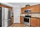 Well-lit kitchen boasts stainless steel appliances, wood cabinets, and stone tile backsplash at 5337 S Ukraine Way, Aurora, CO 80015