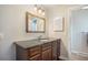 Bathroom featuring a wooden vanity with a granite countertop, a decorative mirror, and modern lighting fixtures at 3257 S Geneva St, Denver, CO 80231