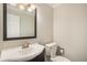 Bright bathroom featuring a modern sink, dark wood-trimmed mirror, and white toilet against a neutral wall color at 3257 S Geneva St, Denver, CO 80231