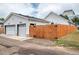 Exterior view of the home featuring a white facade, wooden fence, and a two-car garage at 1721 S Jackson St, Denver, CO 80210