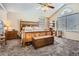 Spacious bedroom features a large wooden bed with chest, ceiling fan, carpet floor, and lots of natural light at 746 Poppywood Dr, Highlands Ranch, CO 80126