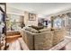 Inviting living room with a brick fireplace, hardwood floors, large sofa, and natural light from a window at 746 Poppywood Dr, Highlands Ranch, CO 80126