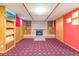 A basement living area with a brick fireplace, built-in shelves, colorful carpet, and paneled walls at 2902 S Meade St, Denver, CO 80236