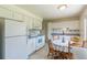 Functional kitchen featuring white appliances and cabinets, with a cozy dining area at 2902 S Meade St, Denver, CO 80236