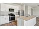 This spacious kitchen features white cabinets, stainless steel appliances and a center island overlooking the living room at 48195 Shetland Dr, Bennett, CO 80102