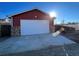 Exterior view of a detached garage with red siding, a white garage door, and a concrete driveway at 1245 Yates St, Denver, CO 80204