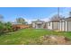 Large backyard with lush grass, sheds, covered patio, and a wood fence at 5491 Lowell Blvd, Denver, CO 80221