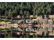 A lakefront log home with chimney surrounded by lush forests and reflecting in the calm water at 6899 Osprey Ln, Evergreen, CO 80439