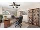 Virtually staged office space with glass desk, shelves, and ceiling fan at 4857 Tarcoola Ln, Highlands Ranch, CO 80130