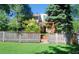 Backyard featuring a wood fence, green grass, trees, stairs and a wooden patio at 6368 S Emporia Cir, Englewood, CO 80111
