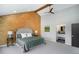 Vaulted ceiling bedroom features a wood accent wall, ceiling fan, ensuite bath, and neutral carpet at 6368 S Emporia Cir, Englewood, CO 80111