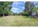 Expansive backyard with mature trees, grassy lawn, a shed, garden beds, and a playset at 1370 S Hudson St, Denver, CO 80222