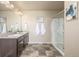 Bathroom showcasing a double vanity, a glass-enclosed shower, neutral walls and tiled floors at 579 Jewel St, Brighton, CO 80603