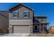 Two-story home features a two-car garage, stone accents, and a covered front porch under a clear blue sky at 579 Jewel St, Brighton, CO 80603