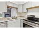 Bright kitchen with stainless steel sink and appliances, complemented by gray cabinetry and views into the living area at 1699 S Trenton St # 174, Denver, CO 80231
