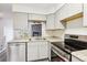 Kitchen featuring a stainless steel dishwasher, stove, and sink, paired with gray cabinets and a view of the living room at 1699 S Trenton St # 174, Denver, CO 80231