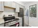 Updated kitchen showcasing gray cabinetry, stainless steel refrigerator, and a window for natural light, creating an inviting space at 1699 S Trenton St # 174, Denver, CO 80231