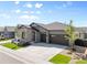 Lovely gray home shows two-car garage, stone facade, xeriscaping, and green lawn at 11383 Autumn Moon St, Littleton, CO 80125