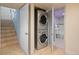 Efficient laundry area with stacked washer and dryer, adjacent to tiled stairs and a doorway to the bathroom at 421 Elati St, Denver, CO 80204