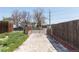 Large backyard with grass, trees, tall fencing, and a gate to enter the area at 4849 Lincoln St, Denver, CO 80216