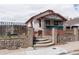 Charming exterior featuring a brick fence, covered front porch, and well-maintained landscaping at 4849 Lincoln St, Denver, CO 80216
