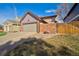 Cozy home featuring a two-car garage and a charming brick wall creating a private front yard space at 8737 Garrison Ct, Arvada, CO 80005