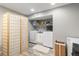 Well-lit laundry area featuring modern washer, dryer, and shelving for storage, plus a unique privacy screen at 400 W Midway Blvd, Broomfield, CO 80020
