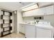 The laundry room has modern washer and dryer units, storage shelves, and a sink at 6474 W Canyon Ave, Littleton, CO 80128