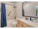 Bright bathroom featuring a tub with shower, light wooden vanity, and tiled walls at 581 Stonemont Dr, Castle Pines, CO 80108