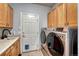 Well-equipped laundry room with modern washer/dryer, sink, and wood cabinets for storage at 581 Stonemont Dr, Castle Pines, CO 80108