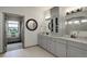 Bright bathroom features double vanity with granite counters, round mirrors, and gray cabinets with storage at 23451 E Rockinghorse Pkwy, Aurora, CO 80016