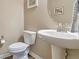 Stylish half-bathroom with a modern sink, toilet, decorative mirror, and neutral wall paint at 11879 W Portland Dr, Littleton, CO 80127