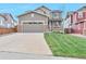 Charming two-story home featuring a well-manicured lawn, gray siding, brick accents, and a two-car garage at 11879 W Portland Dr, Littleton, CO 80127