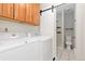 Modern laundry room with a washer, dryer, upper cabinets, and access to a small bathroom at 8367 S Reed St # A3, Littleton, CO 80128