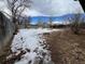 Snowy backyard with a wooden fence and bare trees under a cloudy sky at 1170 W 135Th Dr, Denver, CO 80234