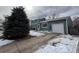 View of two-story house featuring a long driveway, partial snow cover, and mature trees at 1170 W 135Th Dr, Denver, CO 80234