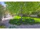 A beautifully landscaped backyard with lush green grass, mature trees, a porch, and meticulous landscaping creating a private outdoor oasis at 3480 Spruce Dell Ct, Castle Rock, CO 80109
