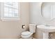 Powder room featuring pedestal sink, toilet, and a round mirror at 3480 Spruce Dell Ct, Castle Rock, CO 80109