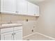 The laundry room is equipped with white cabinets, a utility sink, and tile floors at 3480 Spruce Dell Ct, Castle Rock, CO 80109