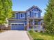 Charming two-story blue home with stone accents, red door and well-maintained landscaping and attached two car garage at 3216 Yale Dr, Broomfield, CO 80023