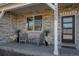 Inviting front porch featuring stone accents, exterior lighting, and a cozy seating area, enhancing the home's curb appeal at 12205 Race St, Northglenn, CO 80241