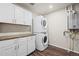 Well-organized laundry room boasts stacked washer/dryer and sleek white cabinetry with a wood-look countertop at 12205 Race St, Northglenn, CO 80241