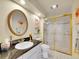 Bright bathroom with an oval mirror and a glass enclosed shower with gold trim at 8312 S Peninsula Dr, Littleton, CO 80120
