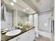 Bathroom featuring double sinks, granite countertop, large mirror, and shower-tub combination at 8312 S Peninsula Dr, Littleton, CO 80120