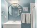 Well-lit bathroom featuring a large round mirror and a white vanity with ample lighting at 11225 W 102Nd Pl, Westminster, CO 80021