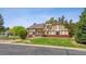 Beautiful front exterior displaying Tudor architecture, mature trees, and manicured lawn at 4855 S Joplin St, Aurora, CO 80015